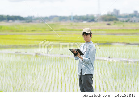 A young man uses a tablet to farm. A young man uses a tablet to farm. 140155815
