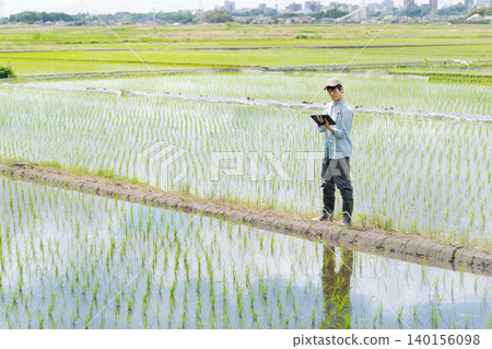 A young man uses a tablet to farm. 140156098