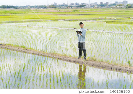 A young man uses a tablet to farm. 140156100