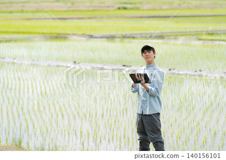 A young man uses a tablet to farm. 140156101
