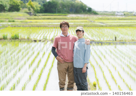 Two farm men with their arms around each other's shoulders on a field path. Two farm men with their arms around each other's shoulders on a field path. 140156463