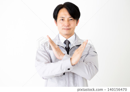 A middle-aged businessman in gray work clothes makes an "X" sign with his hands against a white background. A middle-aged businessman in gray work clothes makes an "X" sign with his hands against a white background. 140156470