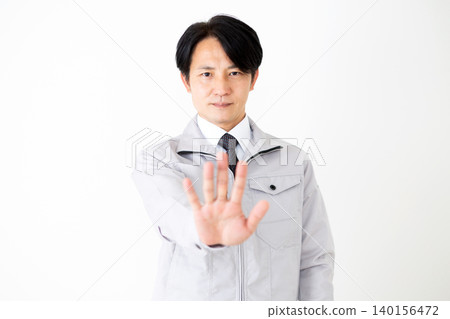一位身穿灰色工作服的中年商人在白色背景前做出拒絕的手勢。 一位身穿灰色工作服的中年商人在白色背景前做出拒絕的手勢。 140156472