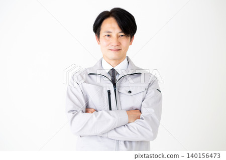 一位身穿灰色工作服的中年商人,雙手交叉放在胸前,背景為白色。 一位身穿灰色工作服的中年商人,雙手交叉放在胸前,背景為白色。 140156473