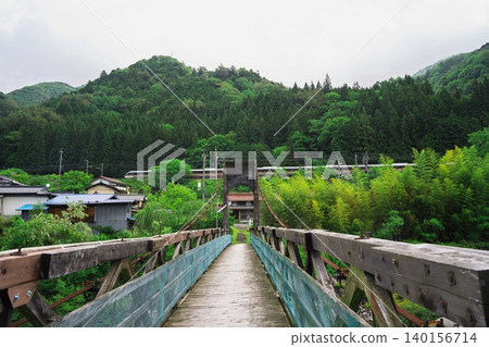 摩羅原橋，一座橫跨木曾川的懸索橋，周圍綠樹環繞，還有一列火車。 140156714