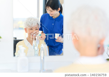 Caregivers who assist seniors with brushing their teeth 140156759
