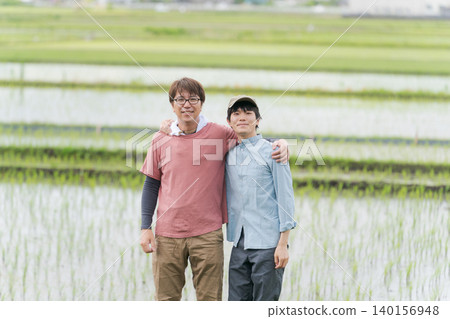 Two farm men with their arms around each other's shoulders on a field path. Two farm men with their arms around each other's shoulders on a field path. 140156948