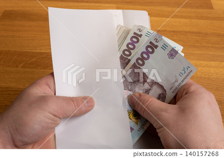 Hands holding envelope with Ukrainian hryvnia cash, bribery or envelope salary concept Hands holding envelope with Ukrainian hryvnia cash, bribery or envelope salary concept 140157268