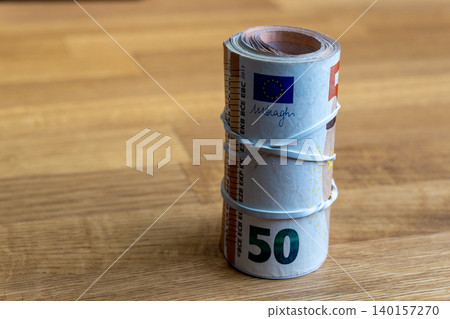 Roll of 50 Euro banknotes tied with rubber band on wooden table close up Roll of 50 Euro banknotes tied with rubber band on wooden table close up 140157270