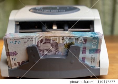 Cash counting machine processing stack of national Ukrainian money bills 140157277