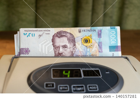 Cash counting machine processing stack of national Ukrainian money bills Cash counting machine processing stack of national Ukrainian money bills 140157281