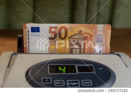 Cash counting machine with 50 Euro banknotes stack close up Cash counting machine with 50 Euro banknotes stack close up 140157282