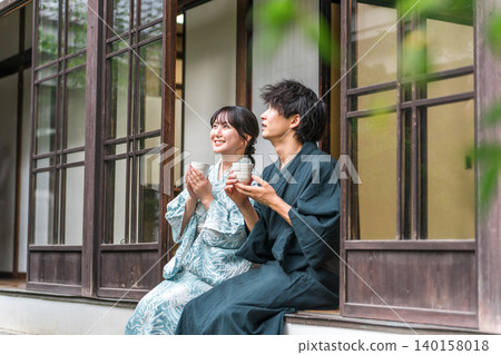 情侶們在旅途中,於溫泉旅館、寺廟住所或老農舍的陽台上品茶。 情侶們在旅途中,於溫泉旅館、寺廟住所或老農舍的陽台上品茶。 140158018