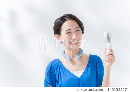 A woman using an ice ring and a handheld fan in the summer. A woman using an ice ring and a handheld fan in the summer. 140158227