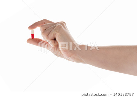 Female hand hold red and white pill isolated on white Female hand hold red and white pill isolated on white 140158797