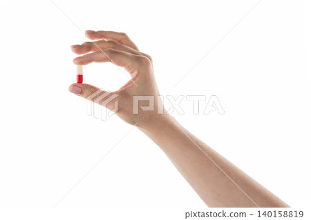 Female hand hold red and white pill isolated on white Female hand hold red and white pill isolated on white 140158819
