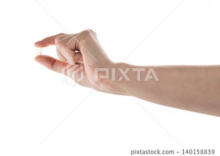Female hand hold transparent pill isolated on white Female hand hold transparent pill isolated on white 140158839