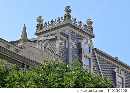 Historic ornate rooftop above green trees 140159306