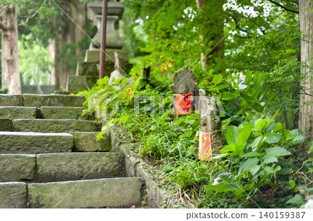 一尊歷史悠久的石佛像靜靜地矗立在通往大仙寺(鳥取縣大仙町)的長長的、長滿青苔的石階旁。 一尊歷史悠久的石佛像靜靜地矗立在通往大仙寺(鳥取縣大仙町)的長長的、長滿青苔的石階旁。 140159387