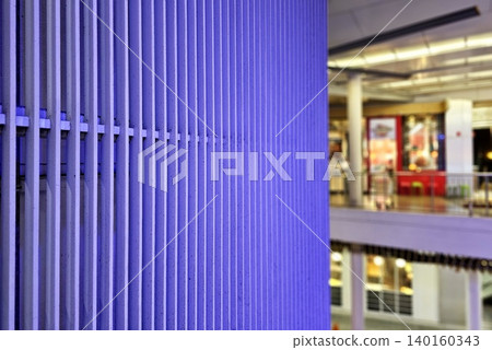 Modern Facade Featuring Parallel Vertical Louvers with Blurred Department Store Background. Modern Facade Featuring Parallel Vertical Louvers with Blurred Department Store Background. 140160343