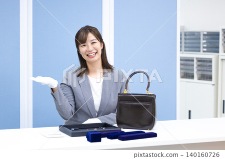 A woman assessing an item at a purchasing company's counter A woman assessing an item at a purchasing company's counter 140160726