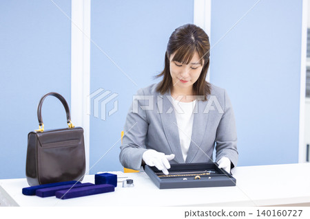 A woman assessing an item at a purchasing company's counter A woman assessing an item at a purchasing company's counter 140160727