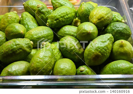 Fresh green citrons or perfume lemons in plastic box container for sale at Temple Street Night Market street food market stall in Hong Kong 140160916