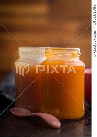 Homemade Baby Food Carrot Puree in Glass Jars with Bowl and Spoon on Dark Surface Homemade Baby Food Carrot Puree in Glass Jars with Bowl and Spoon on Dark Surface 140161388