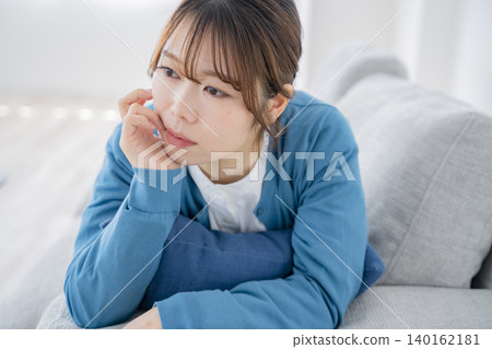 A woman lying on the sofa, lost in thought. A woman lying on the sofa, lost in thought. 140162181