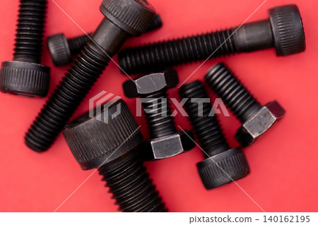 Hexagonal bolt and nut on a red background Hexagonal bolt and nut on a red background 140162195