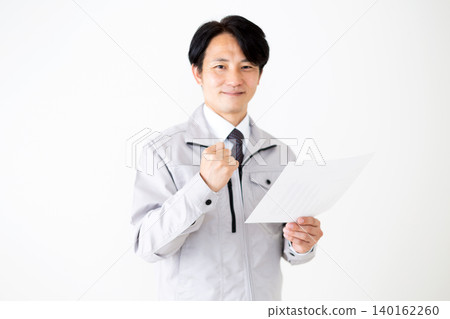 一位身穿灰色工作服的中年商人，在白色背景下看著文件，做出了一個得意的手勢。 140162260