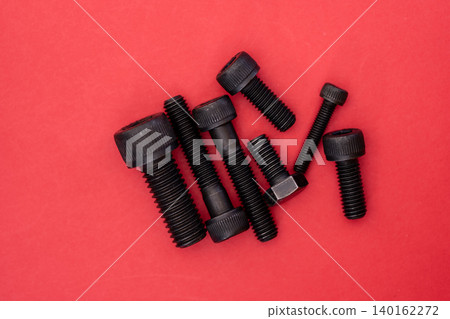 Hexagonal bolt and nut on a red background Hexagonal bolt and nut on a red background 140162272