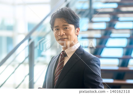 特寫鏡頭,一位面帶微笑的商人,背景是樓梯。 特寫鏡頭,一位面帶微笑的商人,背景是樓梯。 140162318