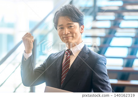 一位身著西裝的商人擺出勝利的姿勢。 一位身著西裝的商人擺出勝利的姿勢。 140162319