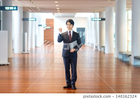 一張商務人士在大廳裡擺出勝利姿勢的全身照。 一張商務人士在大廳裡擺出勝利姿勢的全身照。 140162324
