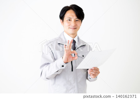 一位身穿灰色工作服的中年商人在白色背景上簽署文件。 140162371