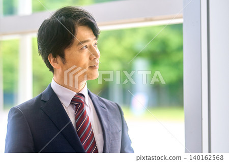 一位身穿西裝的男士側臉凝視遠方。 一位身穿西裝的男士側臉凝視遠方。 140162568