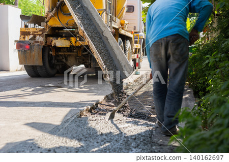 Construction worker leveling fresh wet cement pouring from a mixer truck. Construction worker leveling fresh wet cement pouring from a mixer truck. 140162697