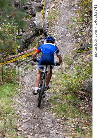 Back mountain biker riding uphill Back mountain biker riding uphill 140162741