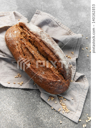 Rustic rye sourdough bread loaf on gray cloth 140162853