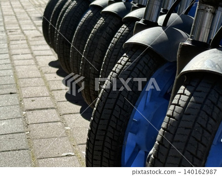 Bicycle rental station in urban area with focus on tires and blue wheel rim Bicycle rental station in urban area with focus on tires and blue wheel rim 140162987