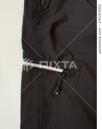 Black zipper detail on dark fabric garment, showcasing clothing texture and design background Black zipper detail on dark fabric garment, showcasing clothing texture and design background 140163002