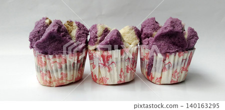 Close-up photo of three purple and white steamed cakes served in floral paper cups. 140163295