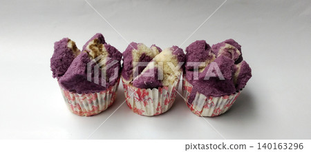 Close-up photo of three purple and white steamed cakes served in floral paper cups. Close-up photo of three purple and white steamed cakes served in floral paper cups. 140163296