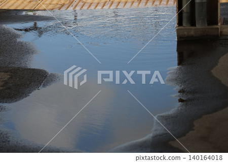 A puddle reflecting the blue sky and white clouds. A puddle reflecting the blue sky and white clouds. 140164018