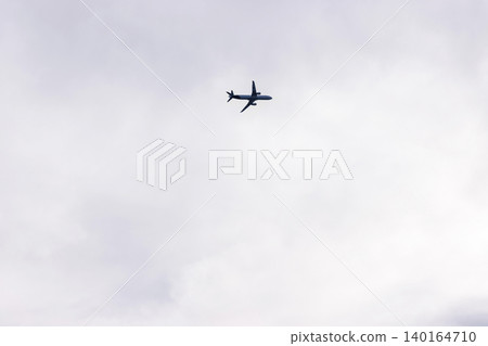 Airplane silhouette flying in cloudy sky with copy space. Minimal aviation and travel background Airplane silhouette flying in cloudy sky with copy space. Minimal aviation and travel background 140164710
