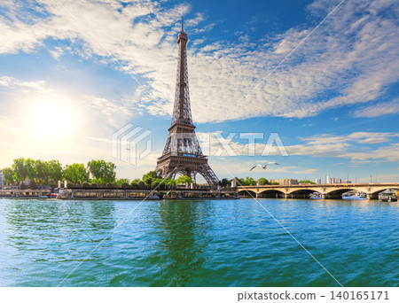 Scenic view of the Eiffel Tower next to a bridge over the Seine River at sunset in Paris, France 140165171