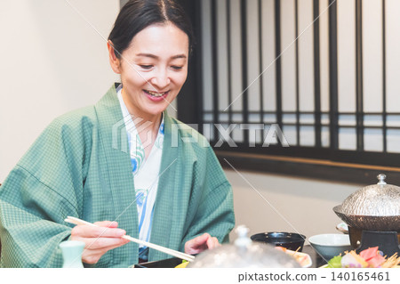 A woman eating dinner at a ryokan (Japanese inn). 140165461