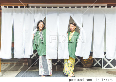 身穿浴衣的女子穿過溫泉旅館的暖簾。 140165470