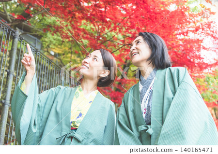 一位身穿浴衣的中年婦女正在欣賞秋葉。 140165471